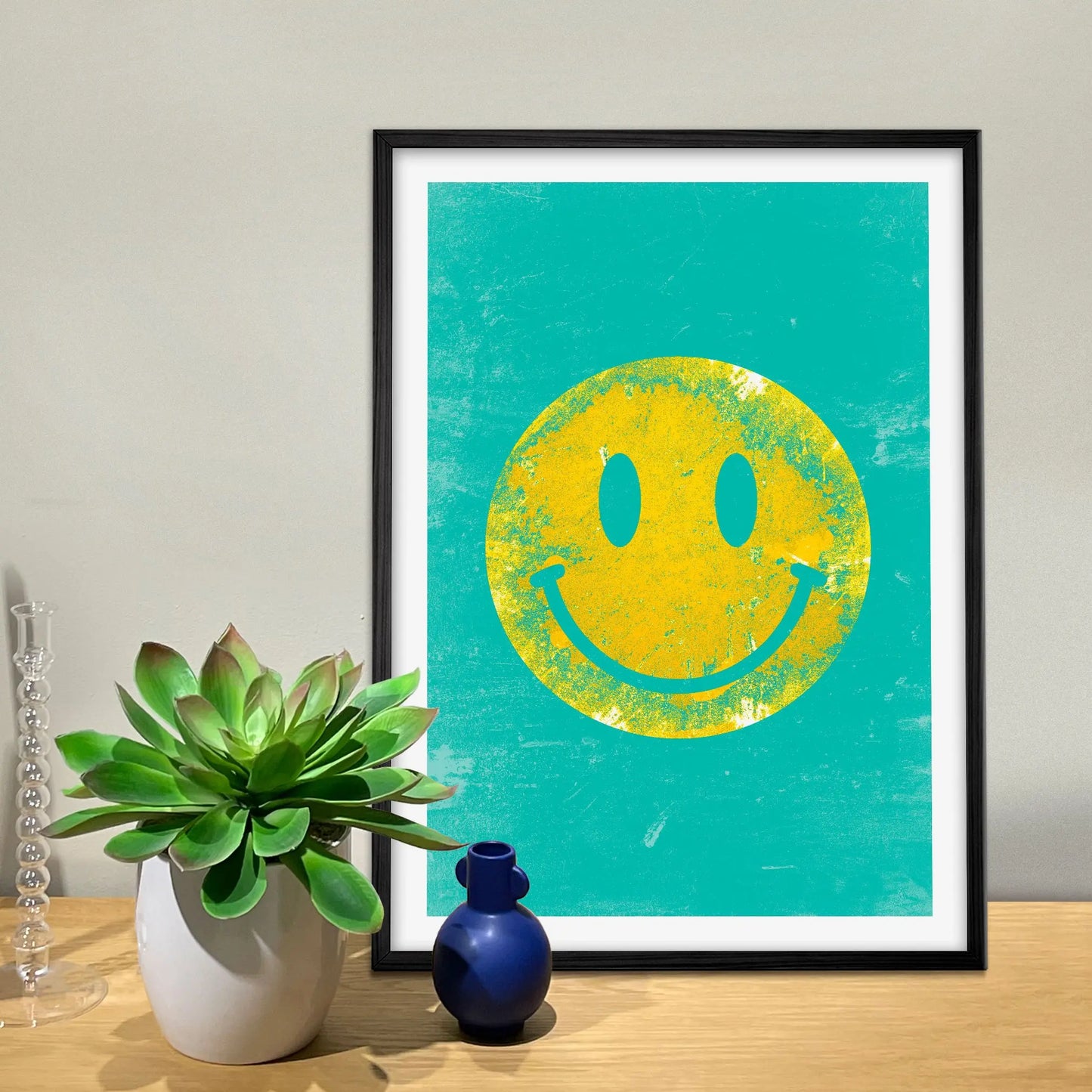 Framed print on sideboard beside a plant and candlestick