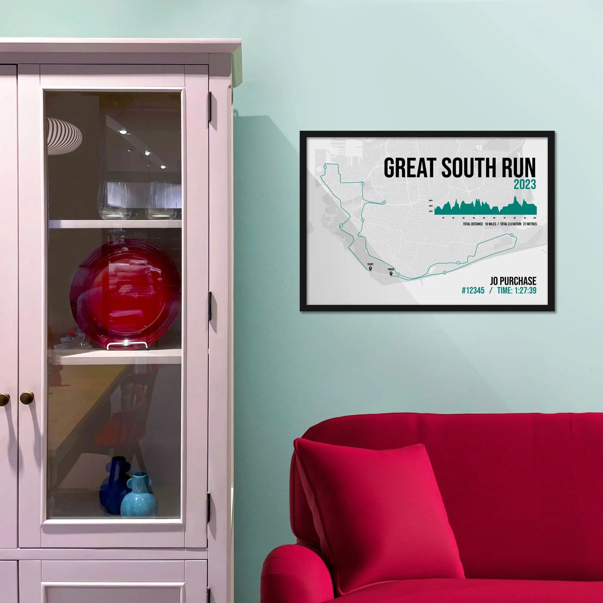 Framed picture on a baby blue wall beside pink shelving