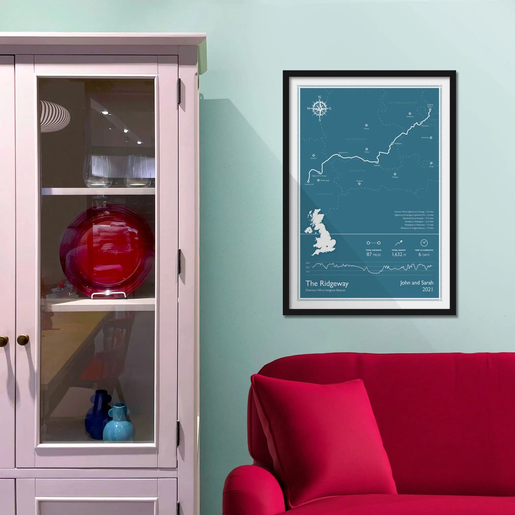 Framed picture on a baby blue wall beside pink shelving