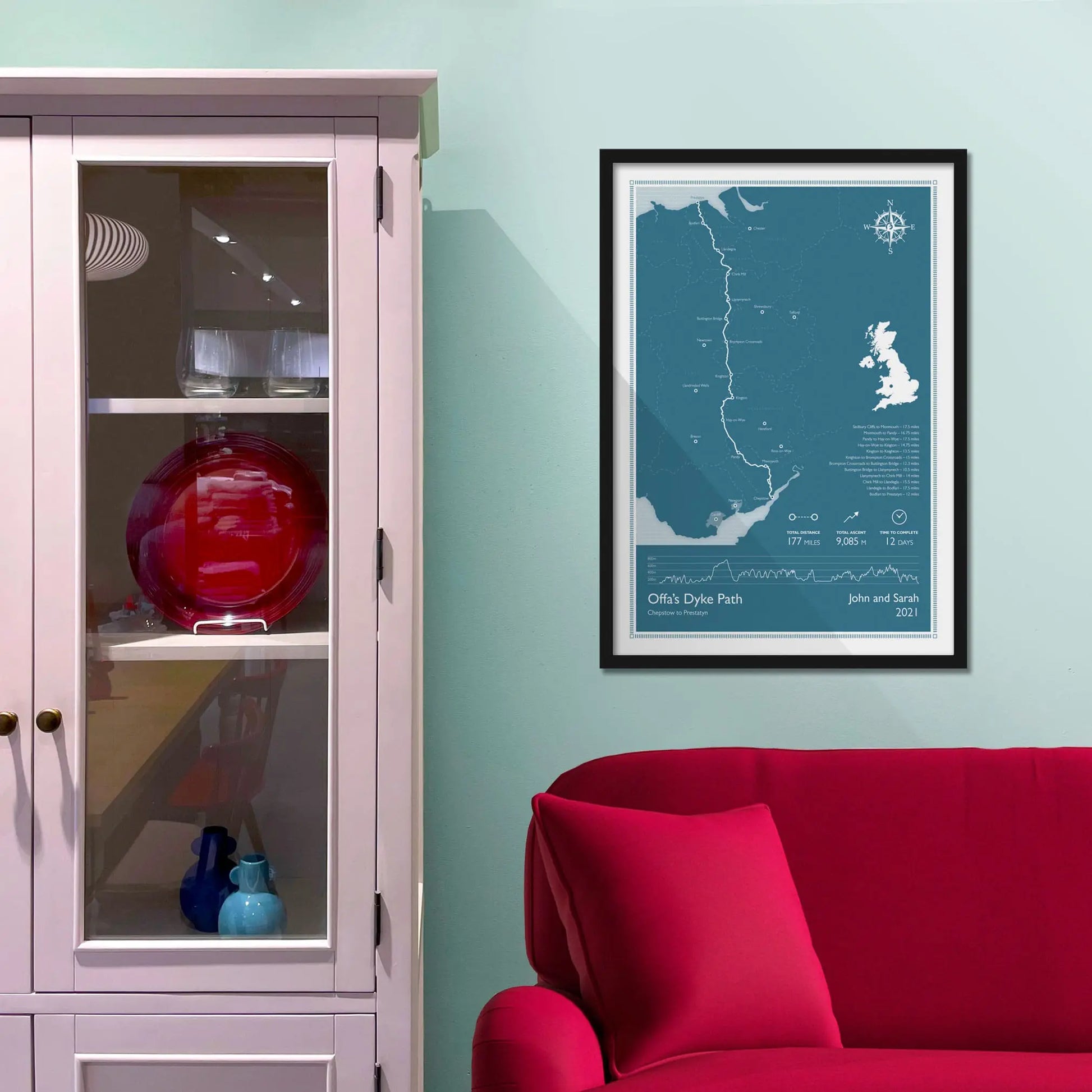 Framed picture on a baby blue wall beside pink shelving