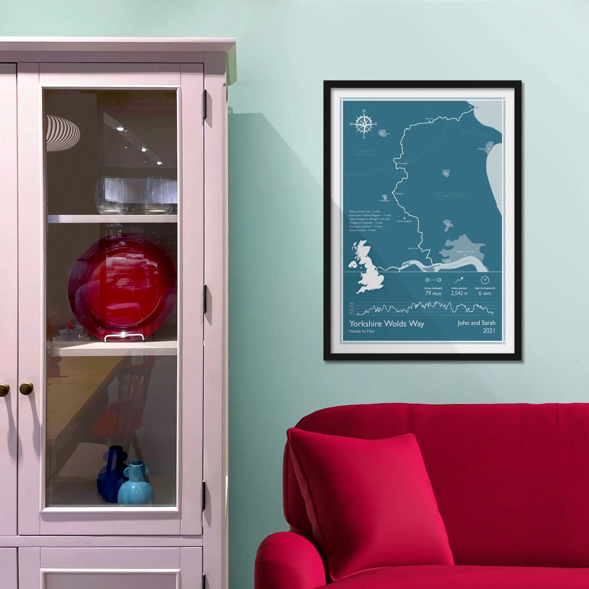 Framed picture on a baby blue wall beside pink shelving