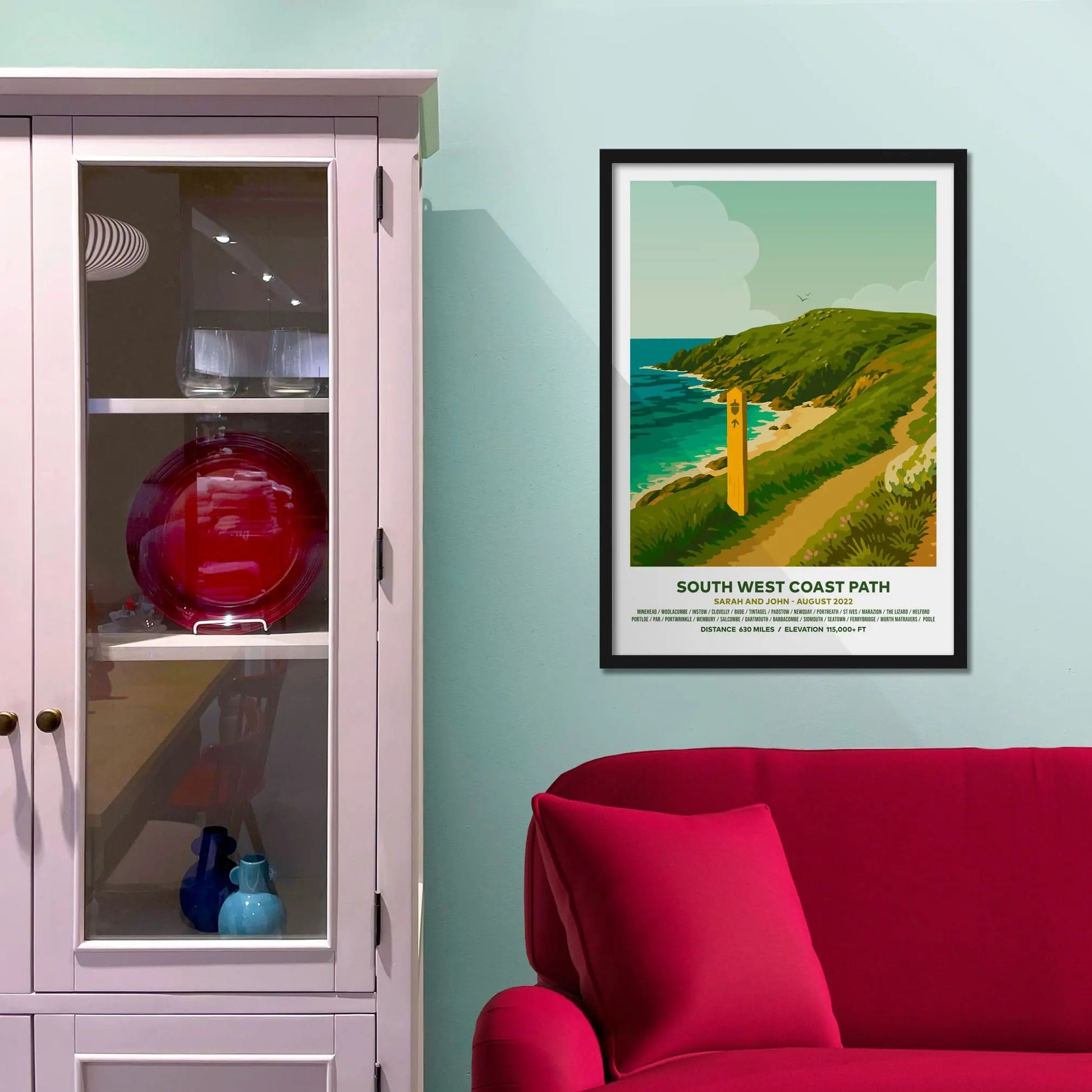 Framed picture on a baby blue wall beside pink shelving