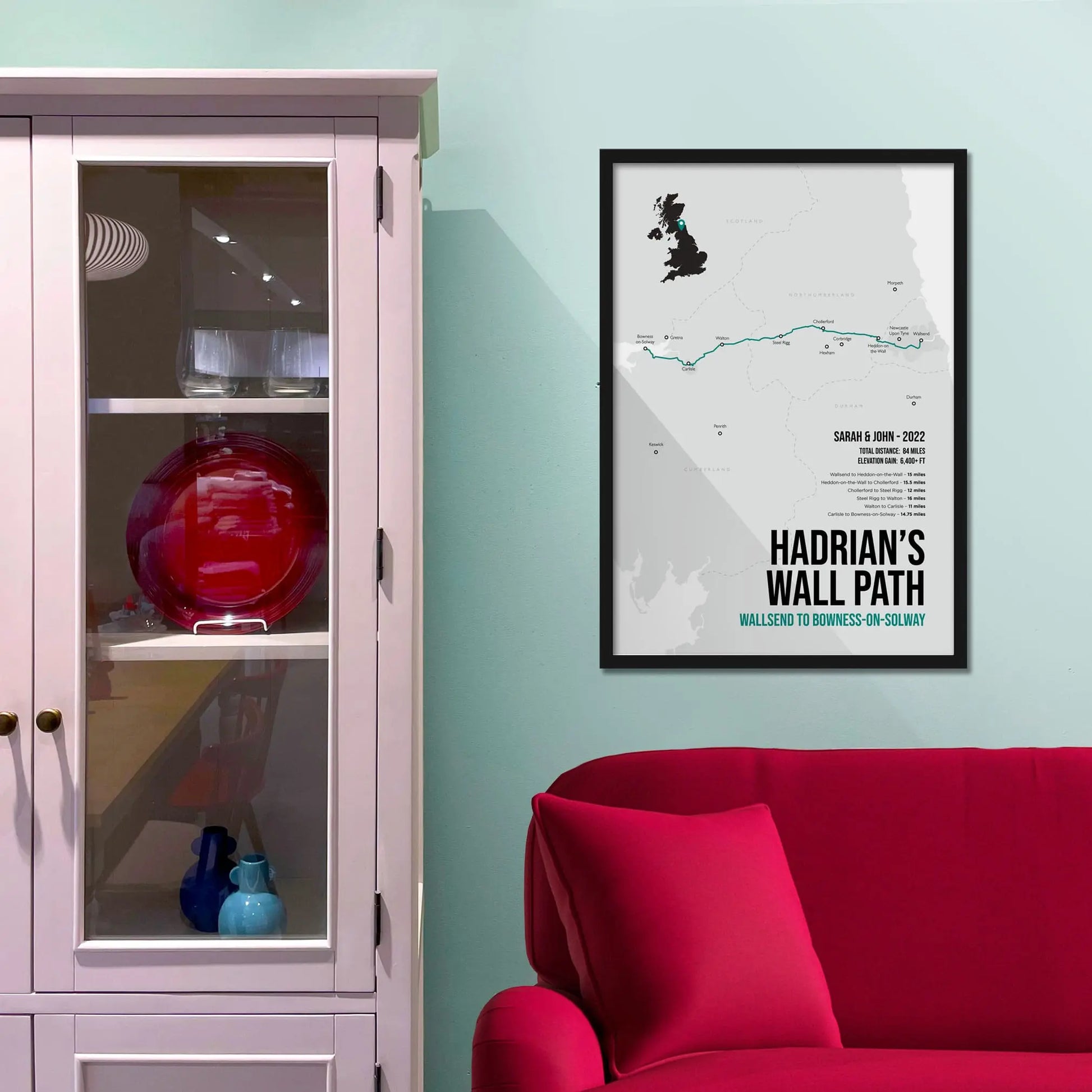 Framed print on light blue wall beside pink shelving unit.