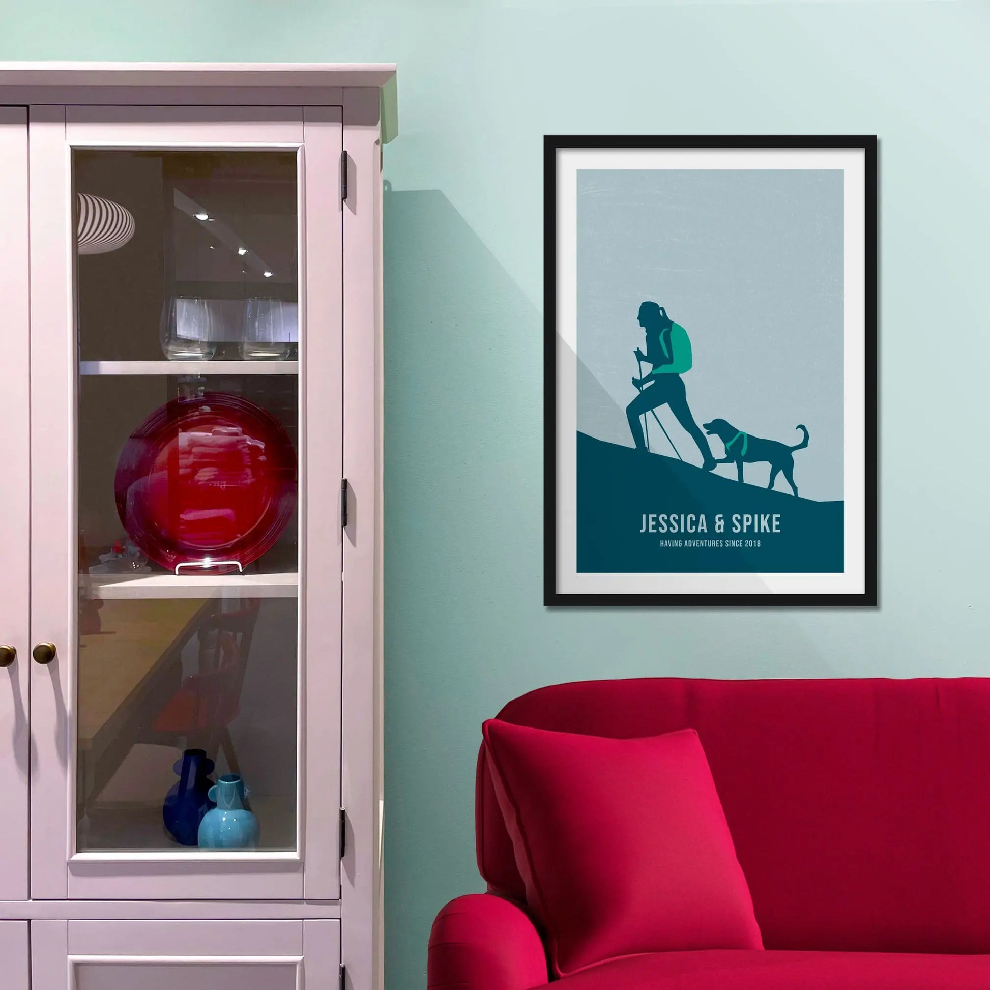 Framed print on light blue wall beside pink shelving unit.