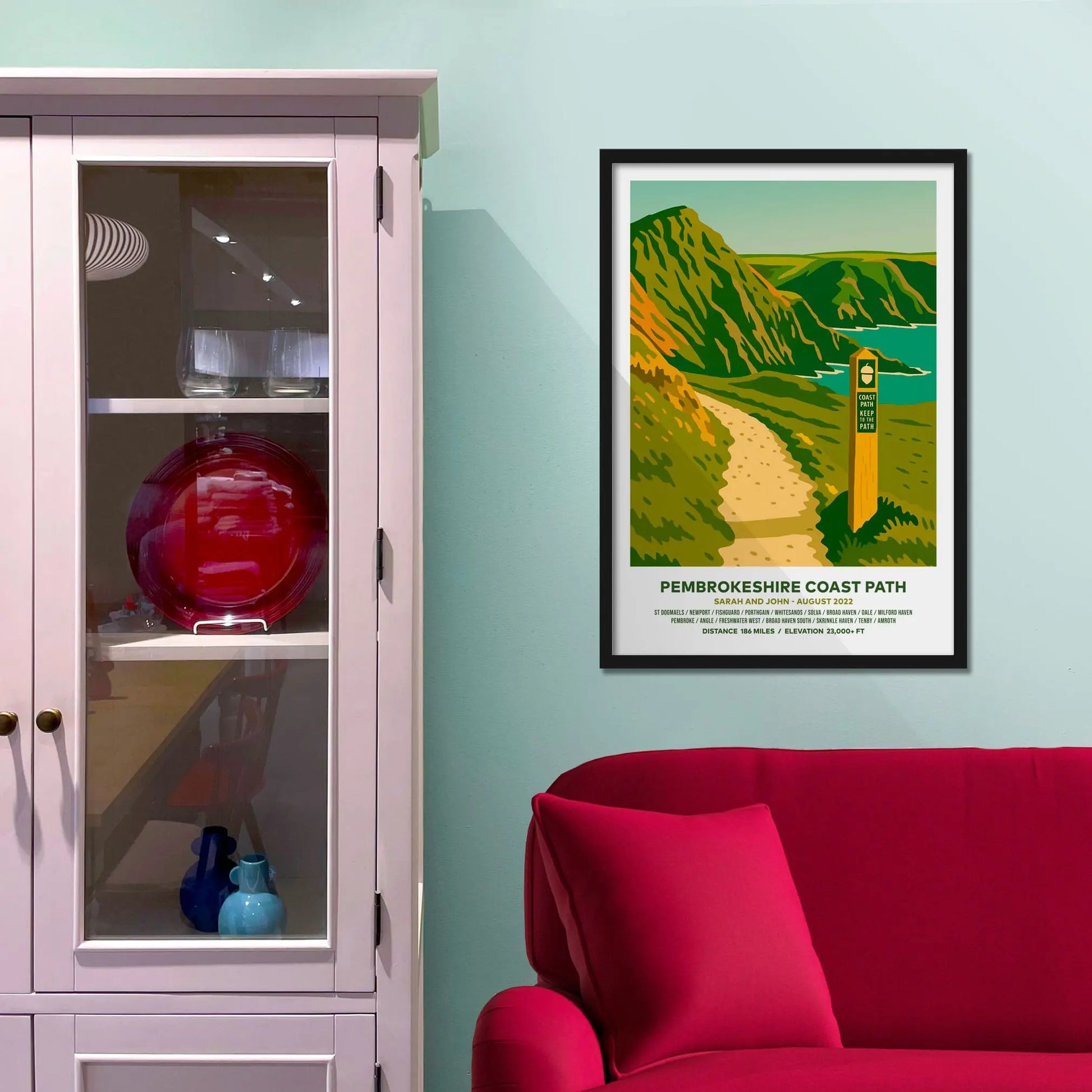 Framed picture on a baby blue wall beside pink shelving