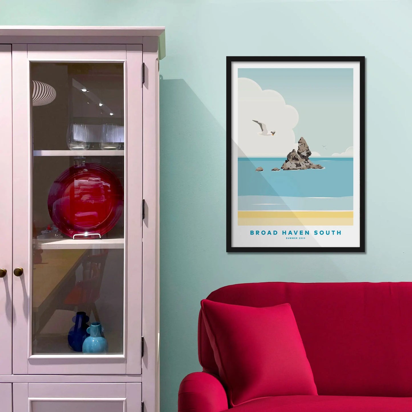 Framed picture on a baby blue wall beside pink shelving