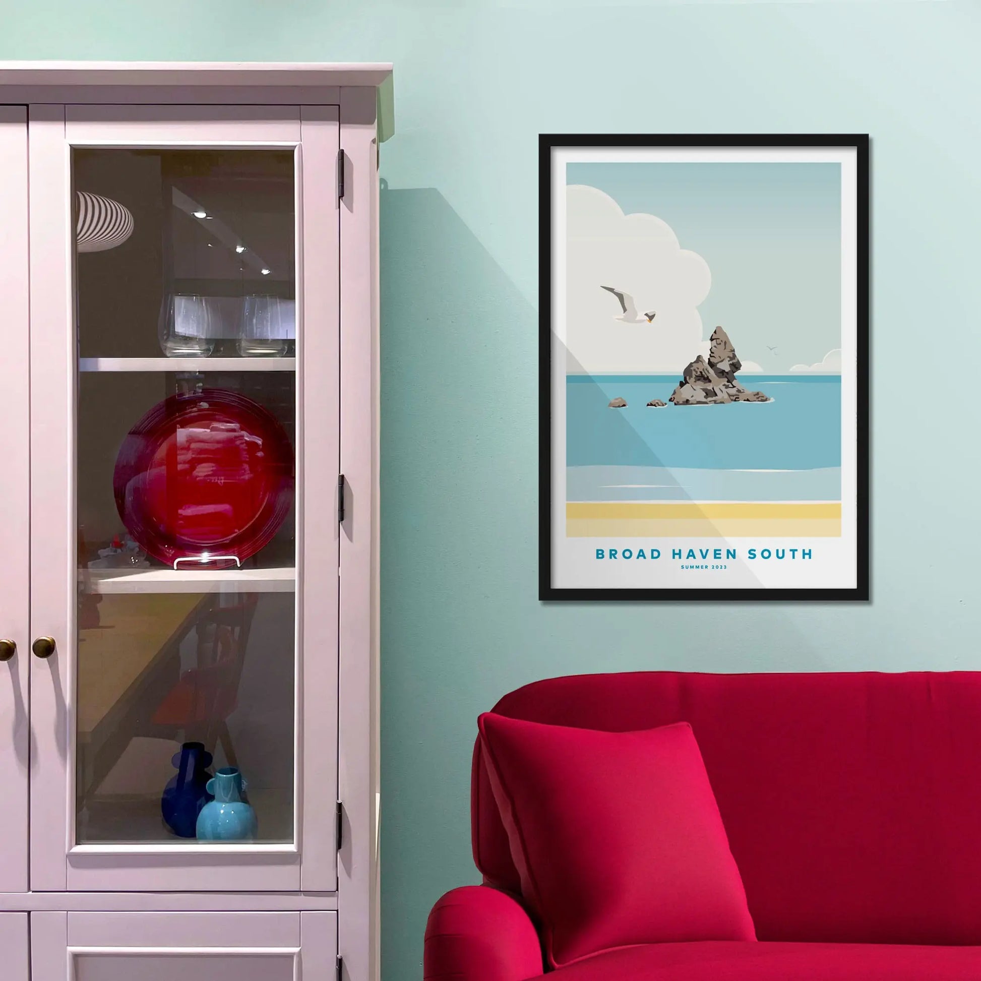 Framed picture on a baby blue wall beside pink shelving