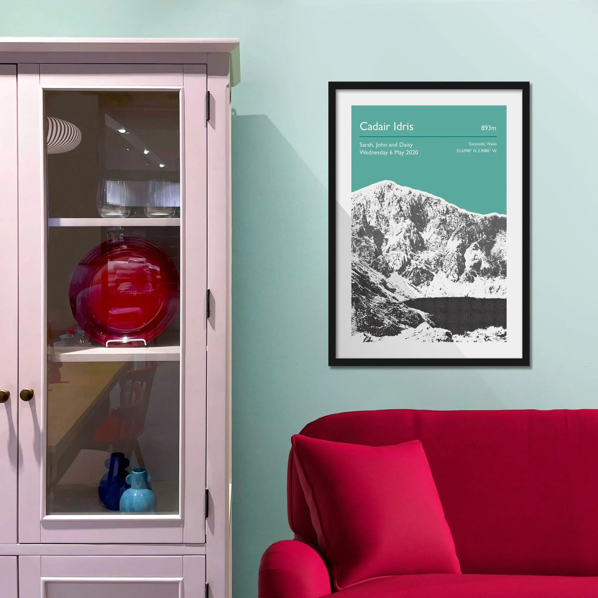 Framed picture on a baby blue wall beside pink shelving