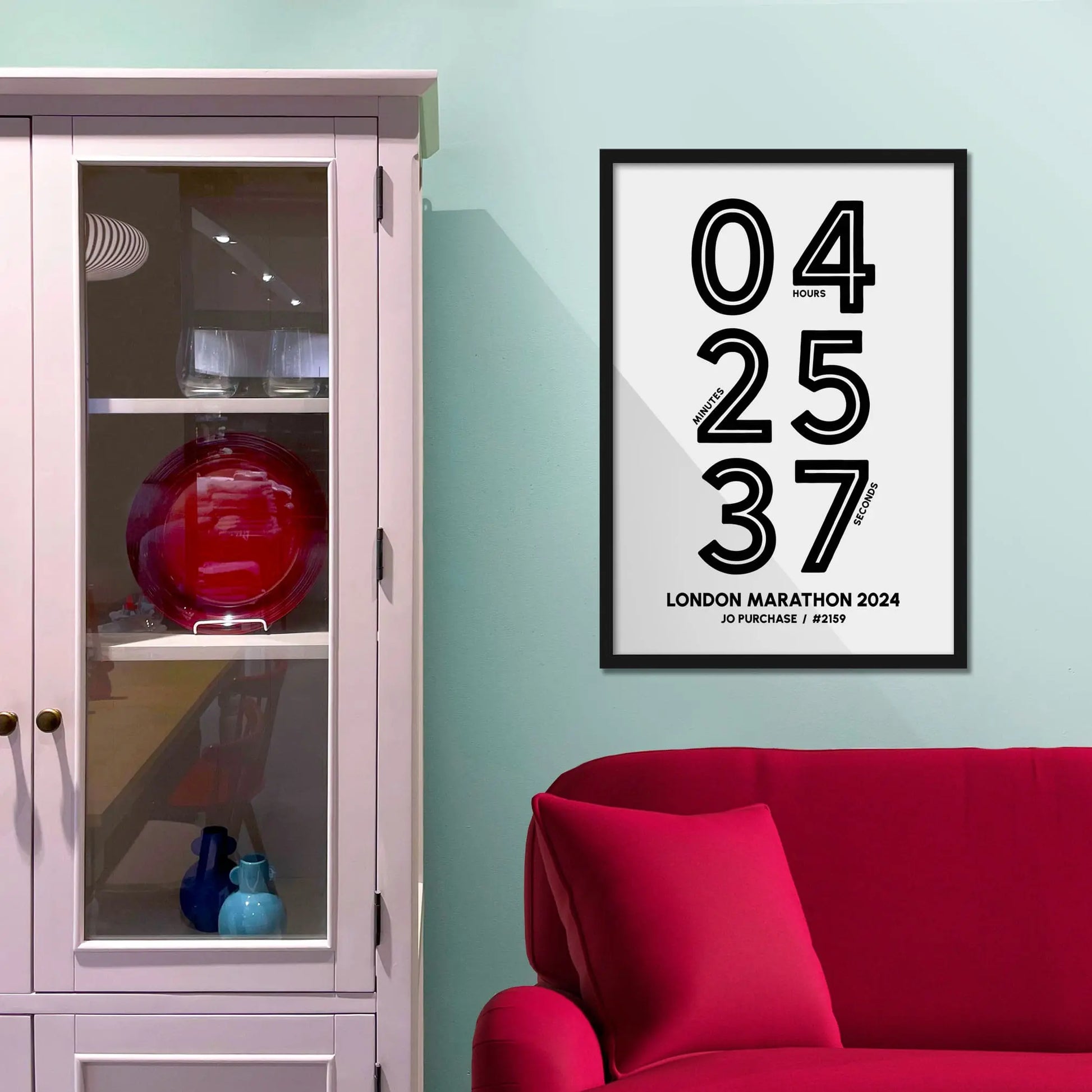 Framed picture on a baby blue wall beside pink shelving