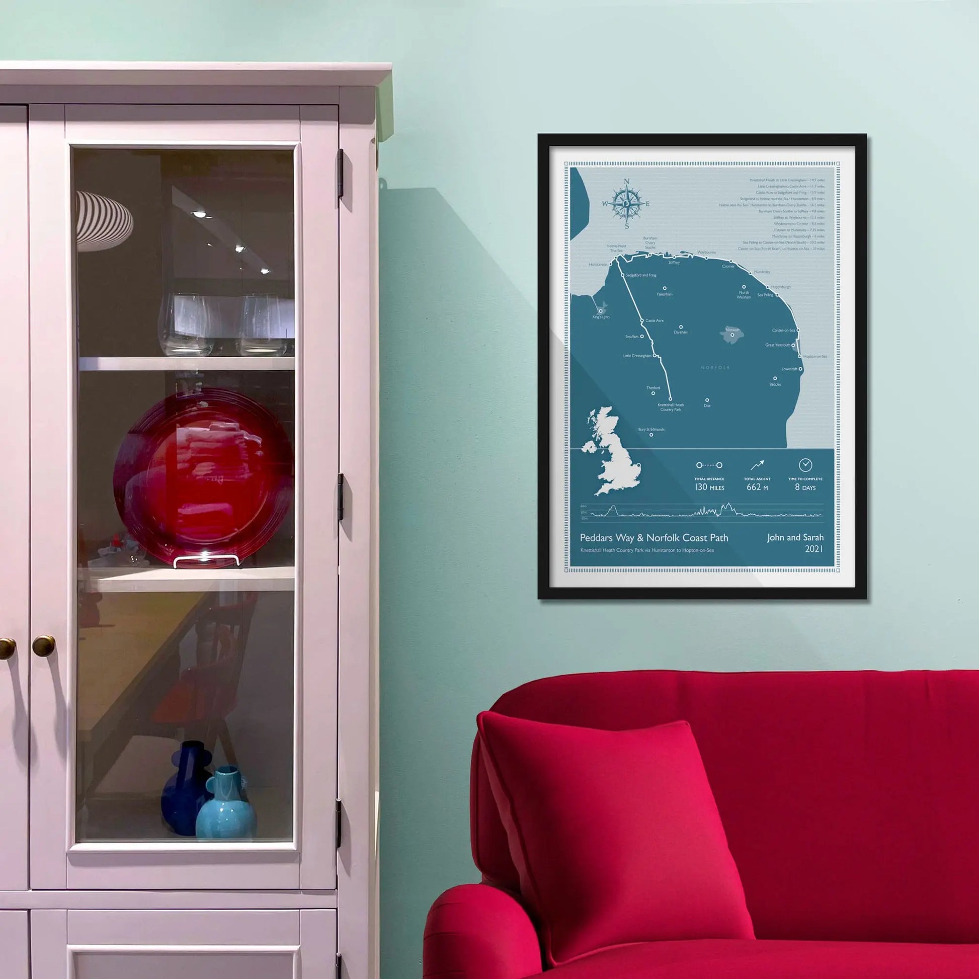 Framed picture on a baby blue wall beside pink shelving