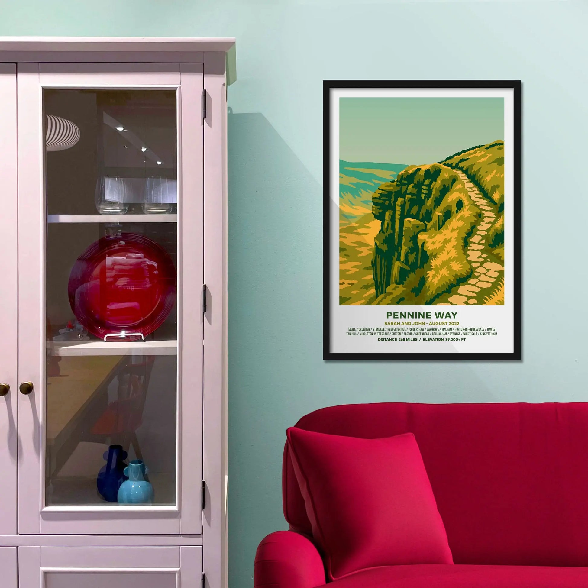 Framed picture on a baby blue wall beside pink shelving