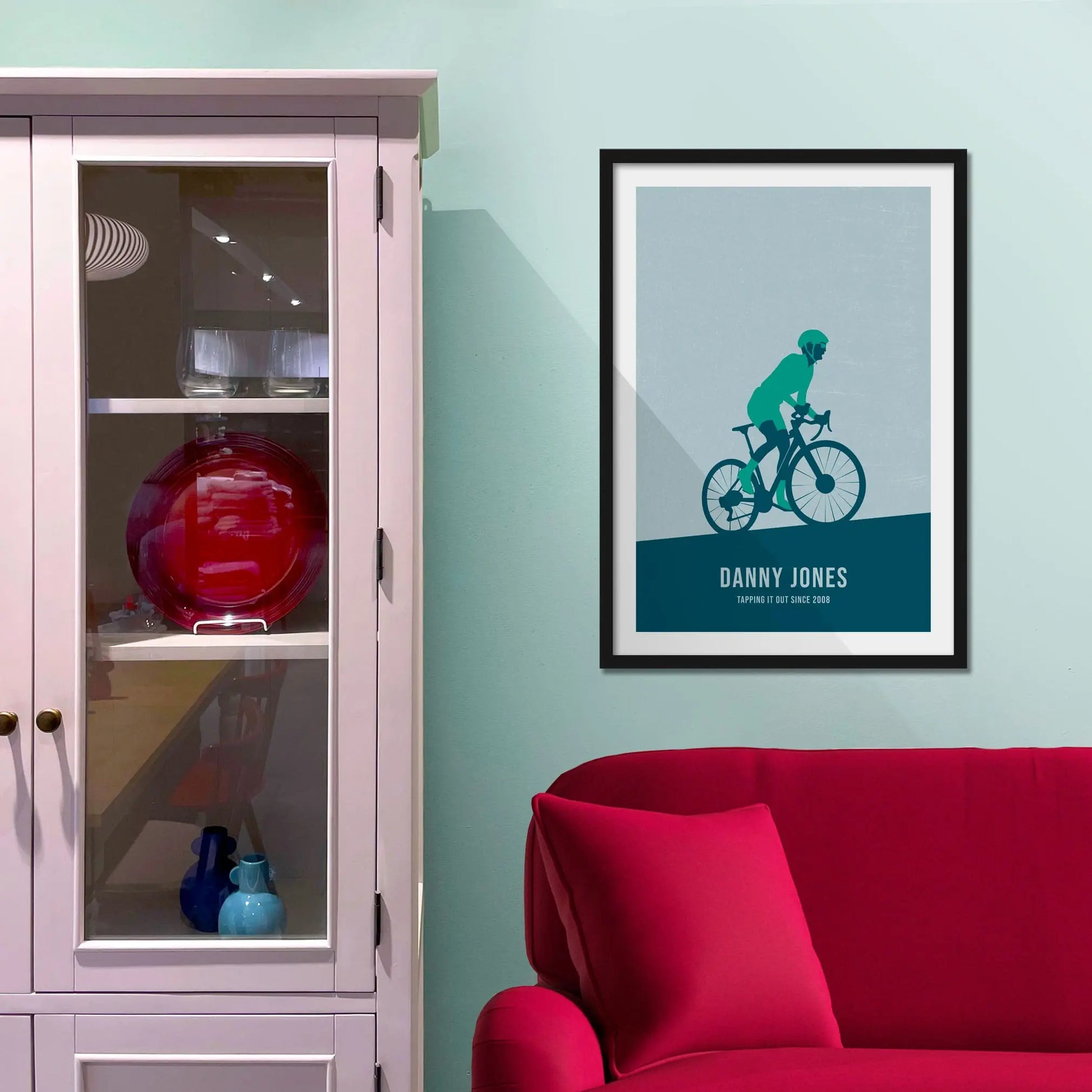 Framed print on light blue wall beside pink shelving unit.