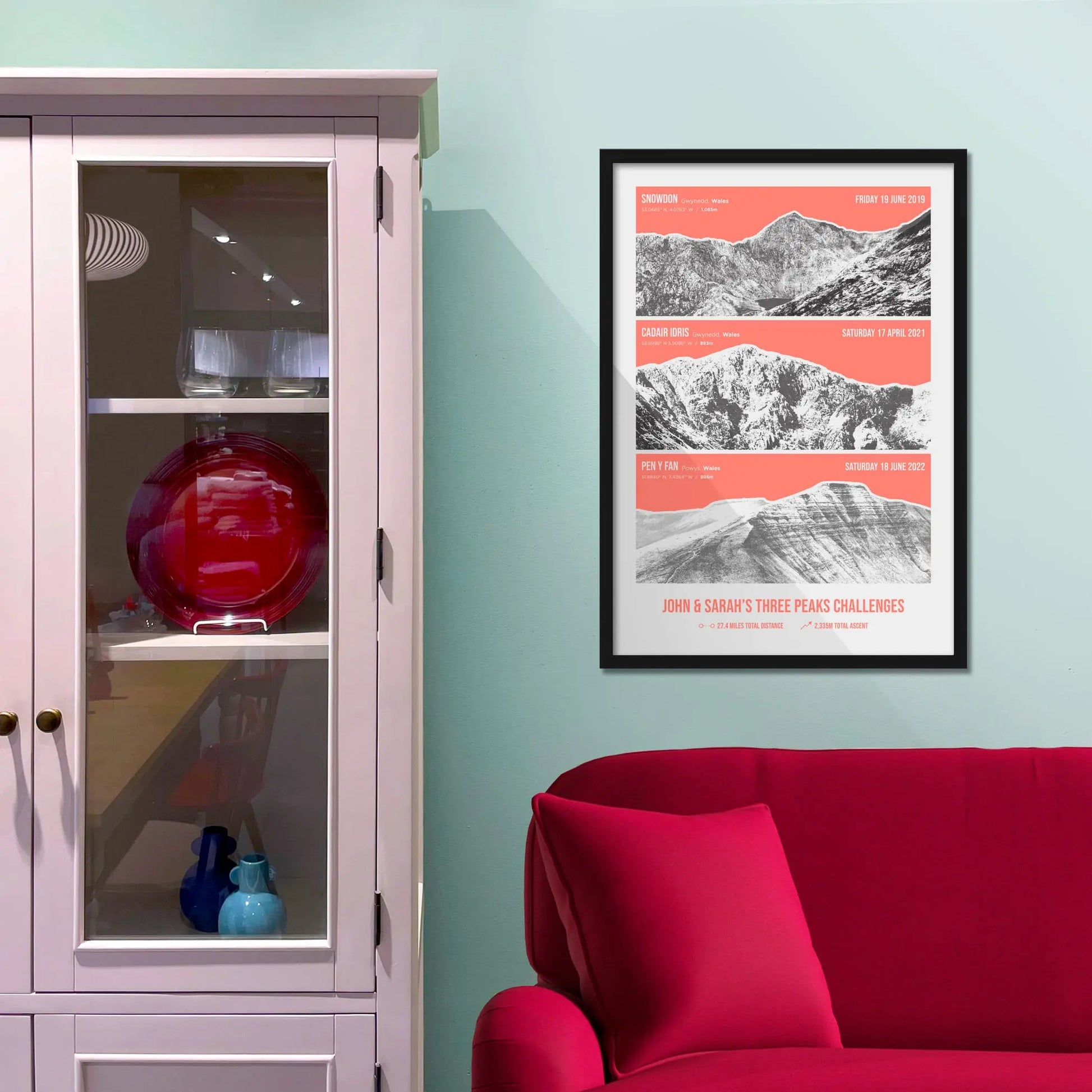Framed print on baby blue wall beside pink shelves and behind a red sofa