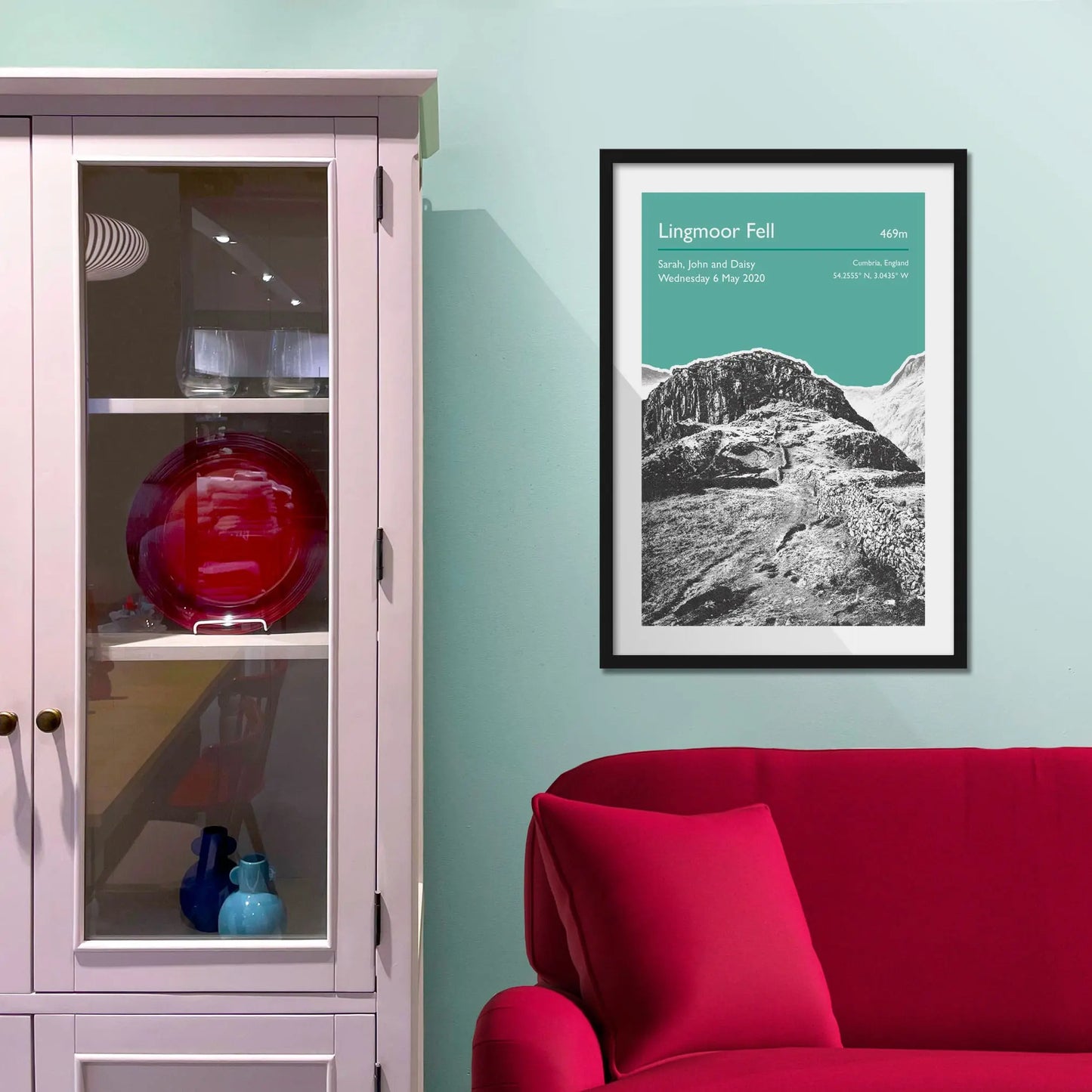 Framed picture on a baby blue wall beside pink shelving