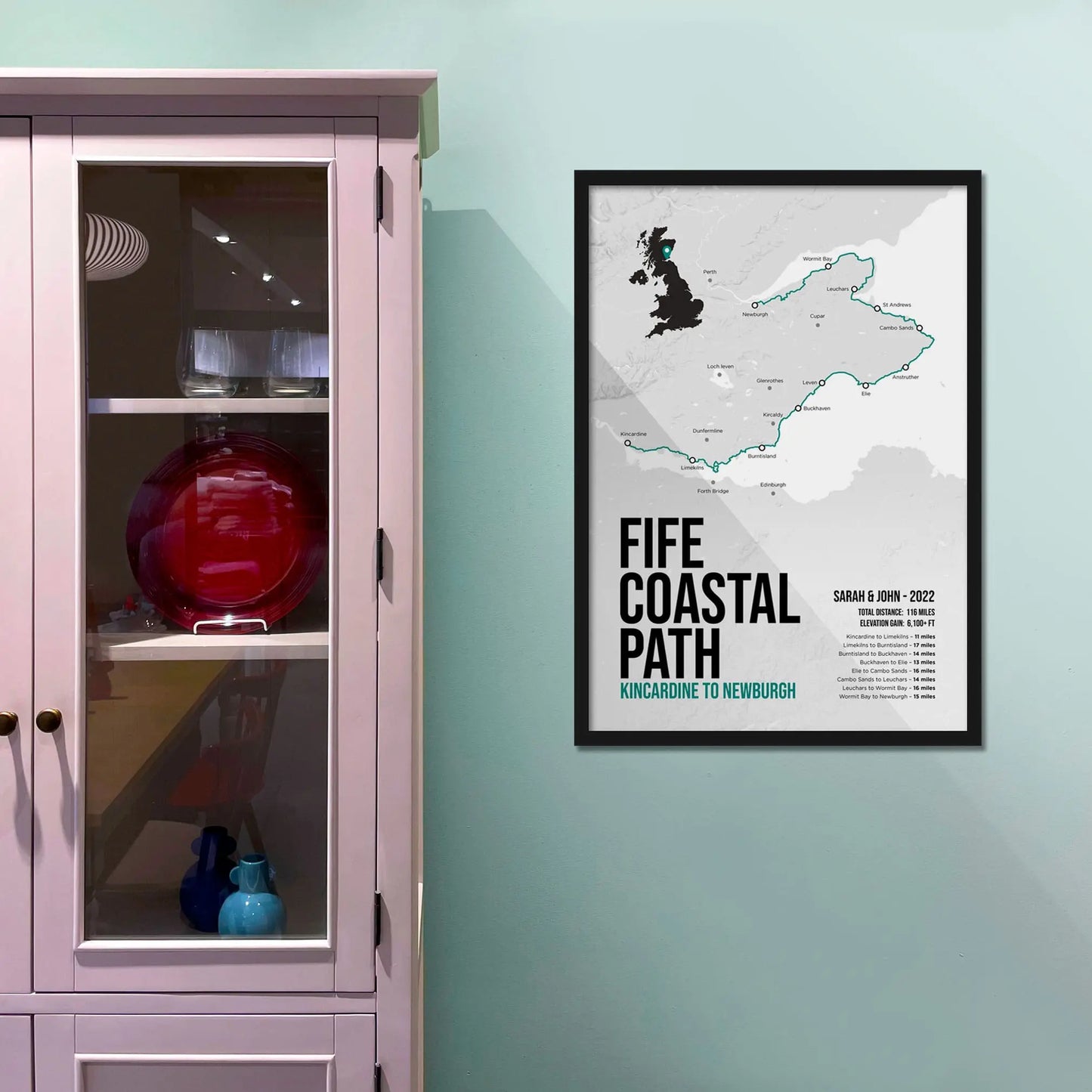 Framed print on light blue wall beside pink shelving unit.