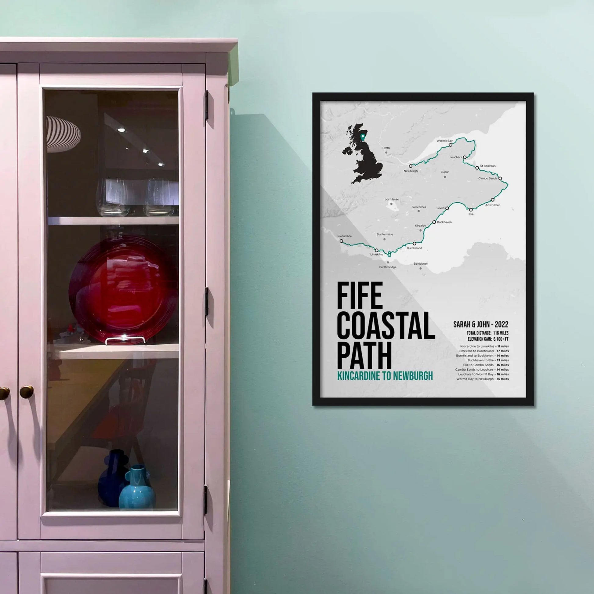 Framed print on light blue wall beside pink shelving unit.