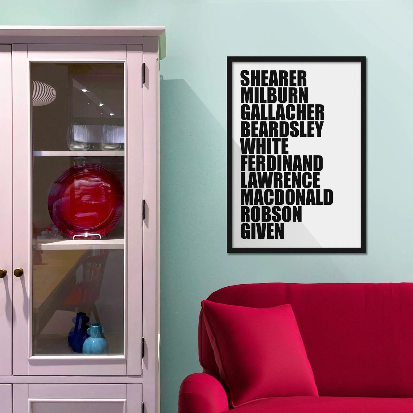 Framed picture on blue wall beside shelves above a red sofa
