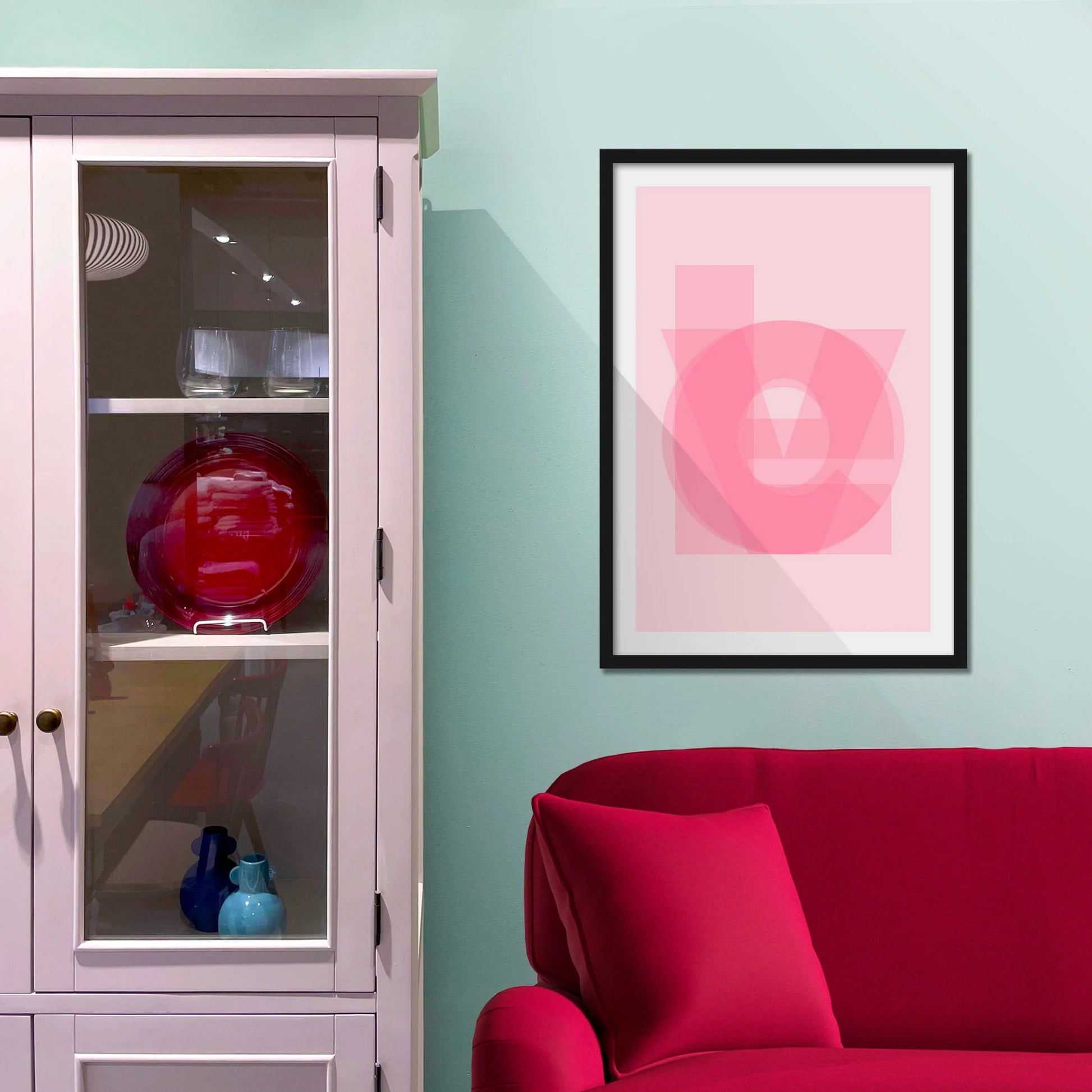 Framed picture on blue wall beside shelves above a red sofa