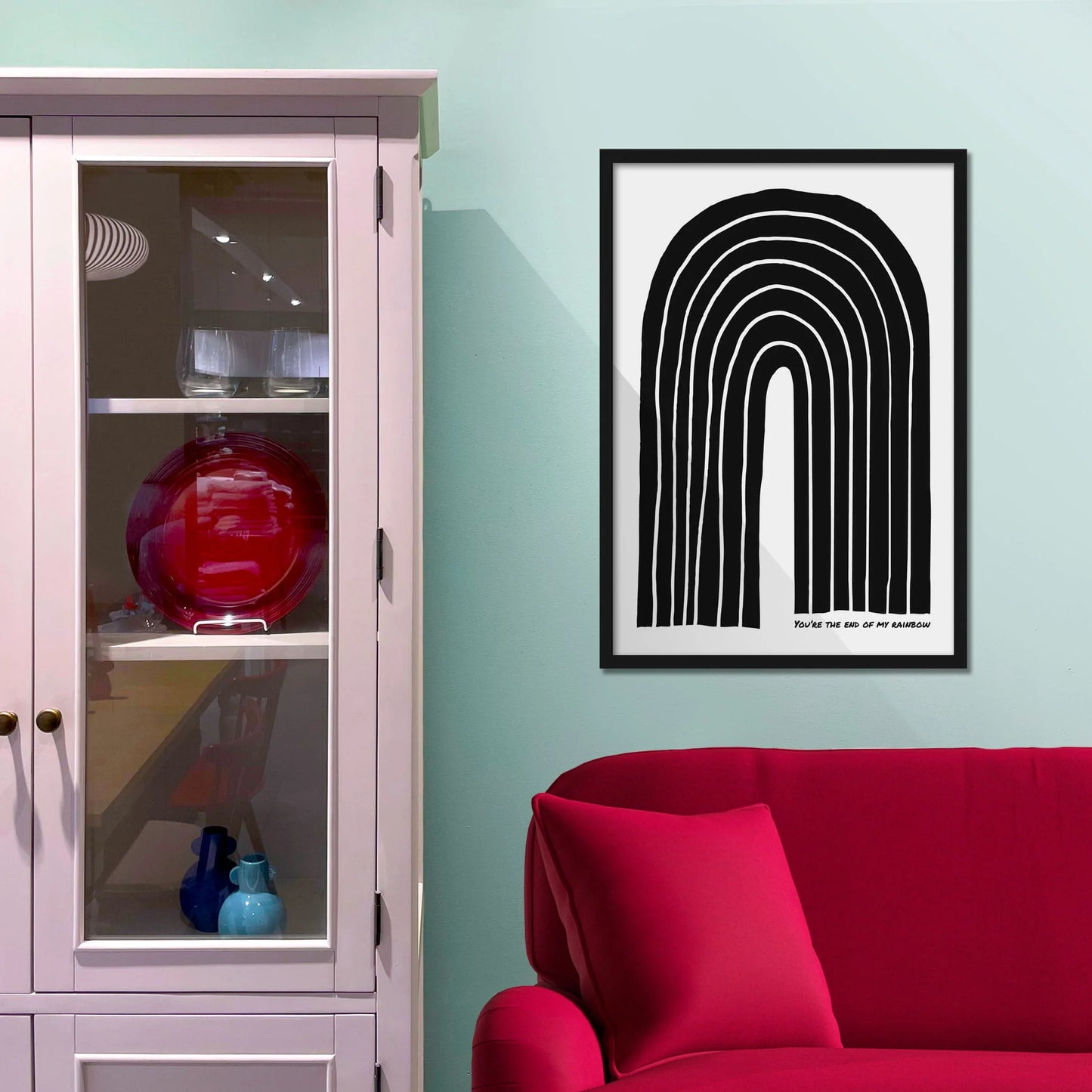 Framed picture on blue wall beside shelves above a red sofa