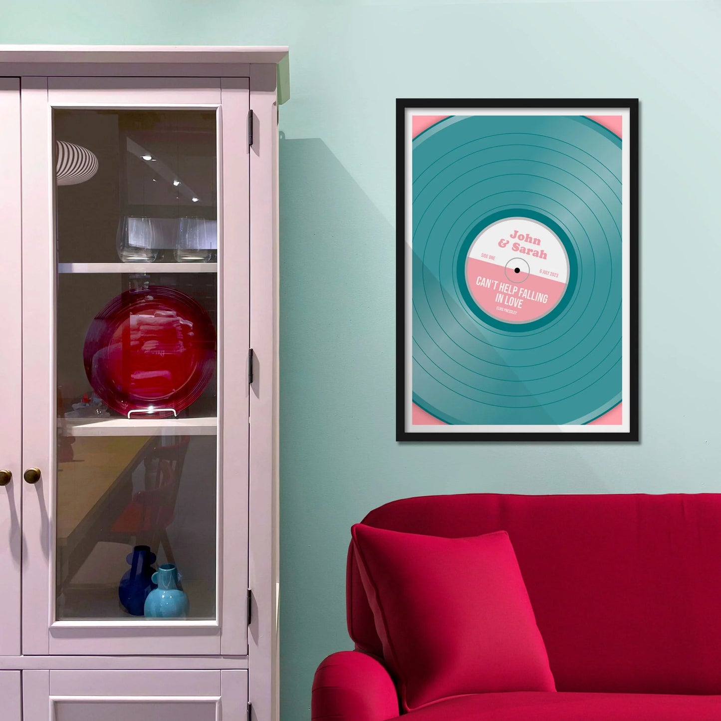 Framed picture on blue wall beside shelves above a red sofa