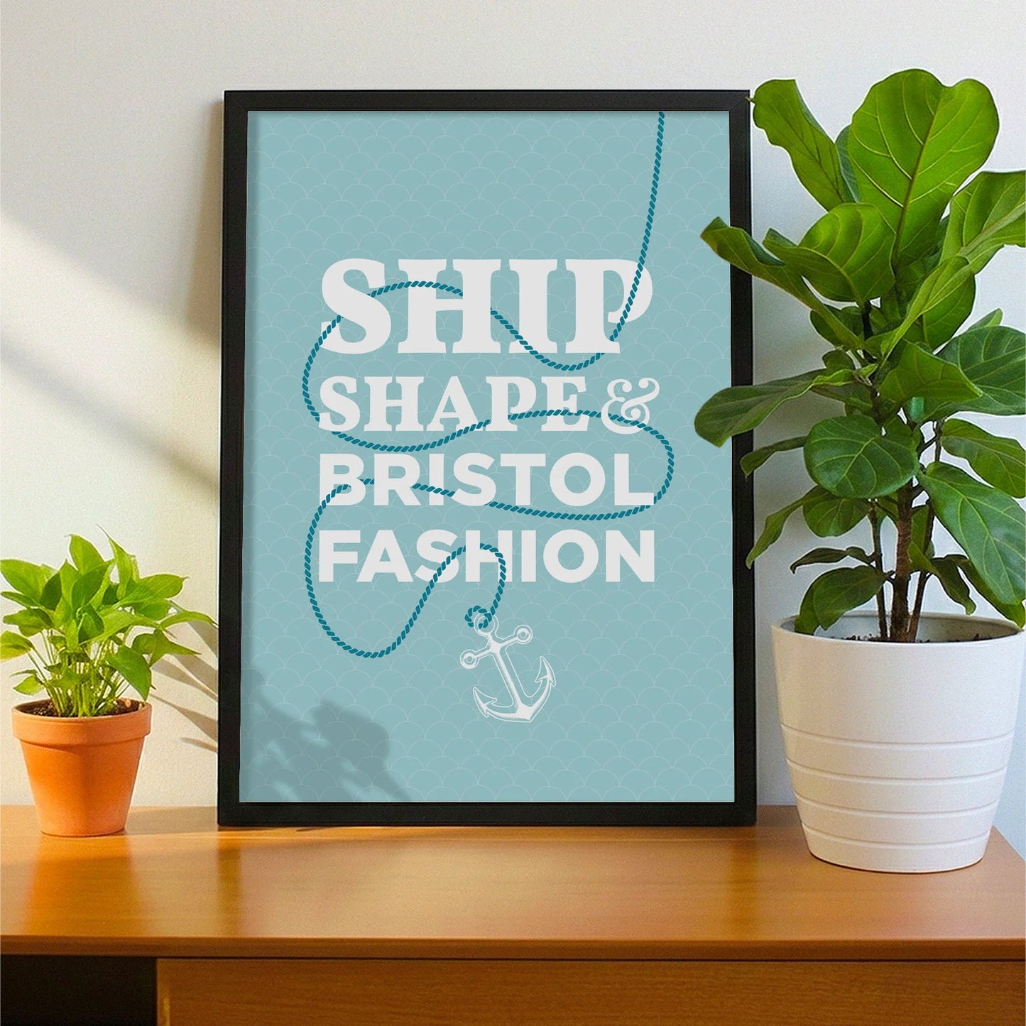 Framed print on sideboard beside a plant