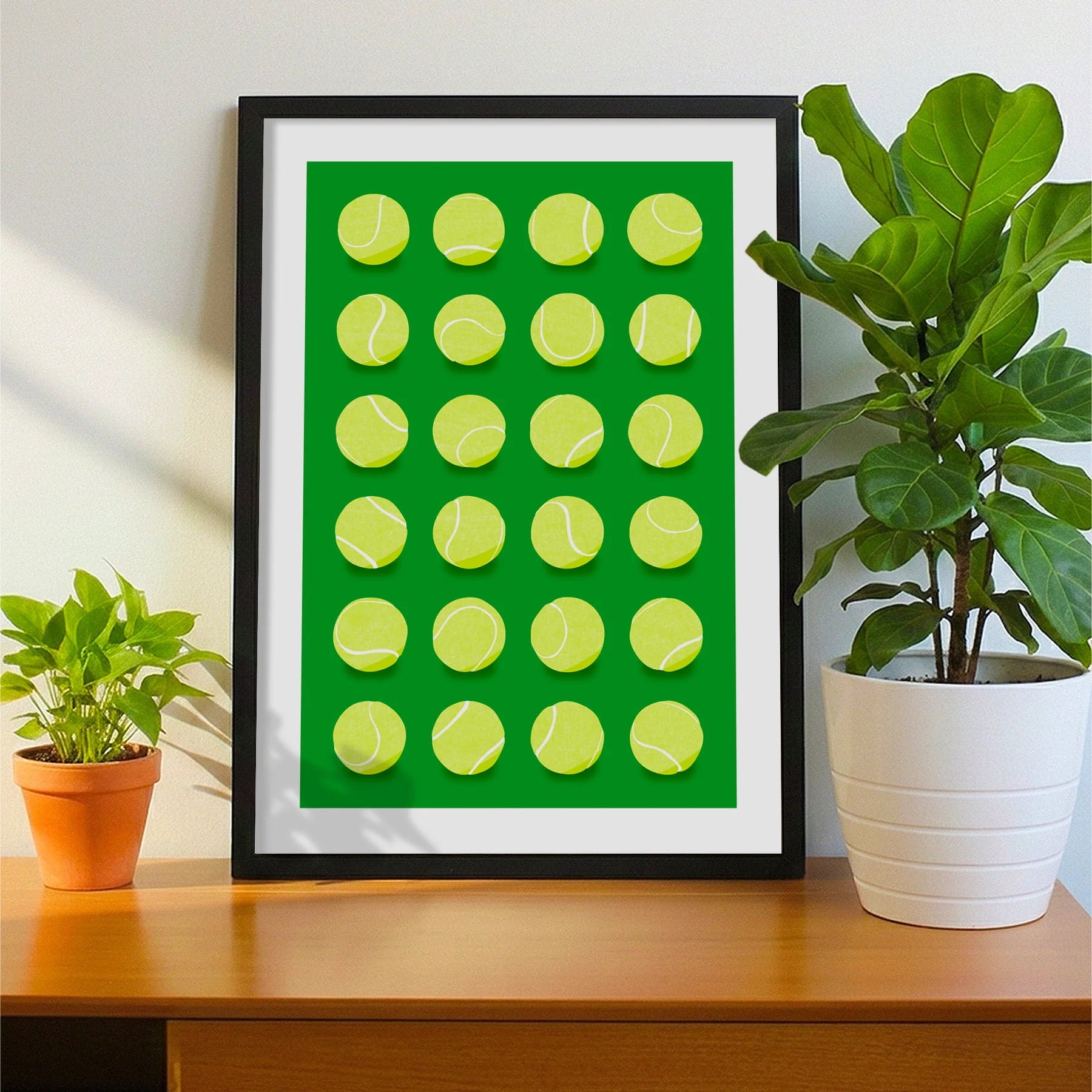 Framed print on sideboard beside a plant