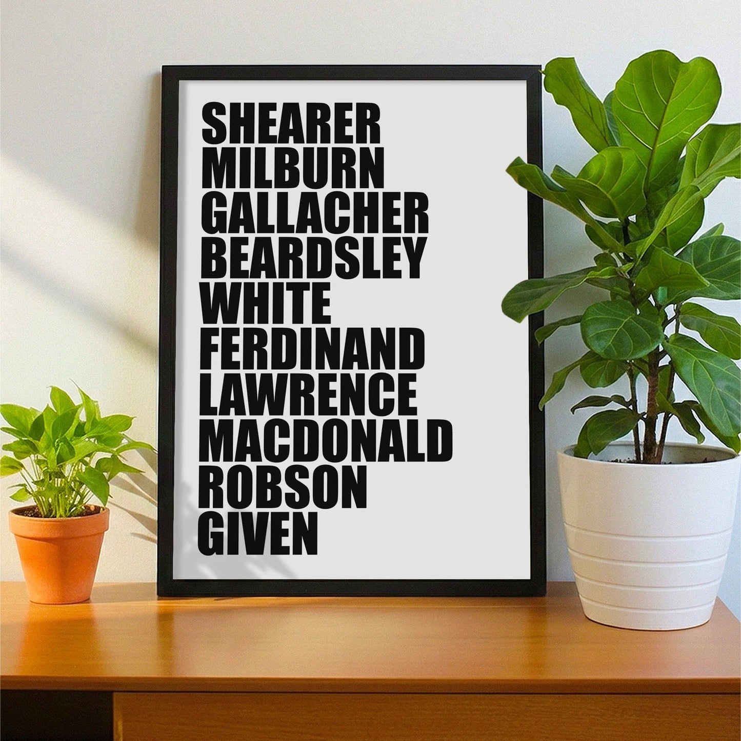 Framed print on sideboard beside a plant