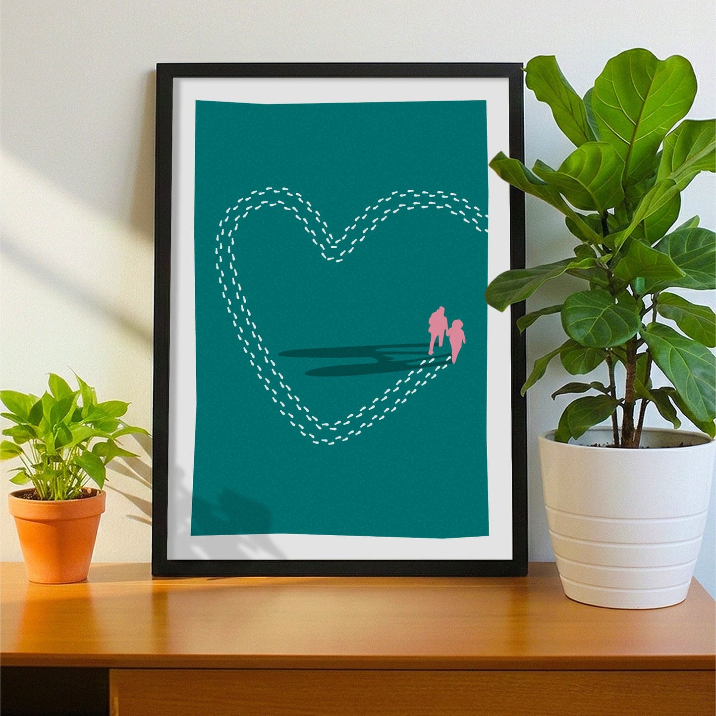 Framed print on sideboard beside a plant