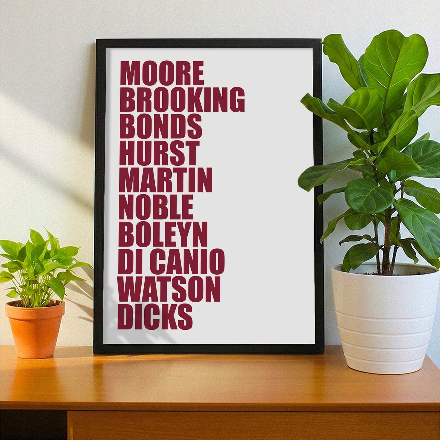Framed print on sideboard beside a plant