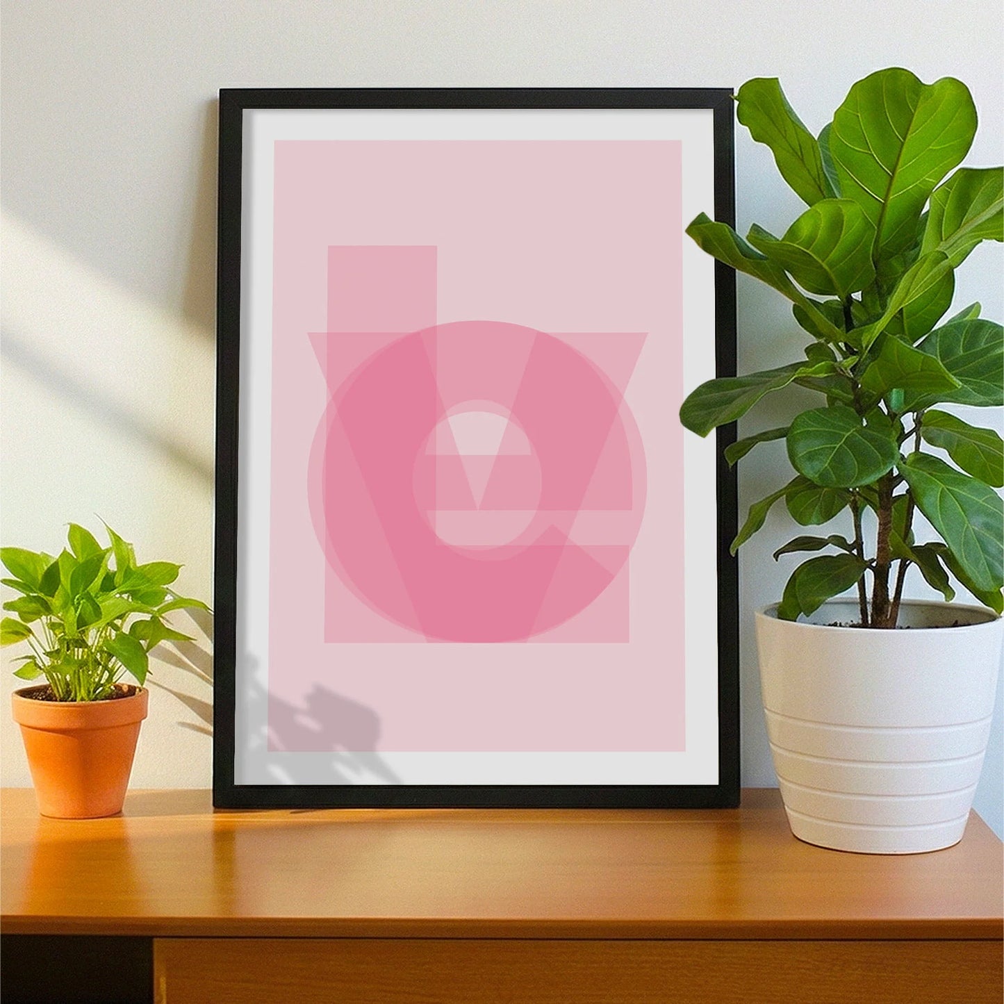 Framed print on sideboard beside a plant