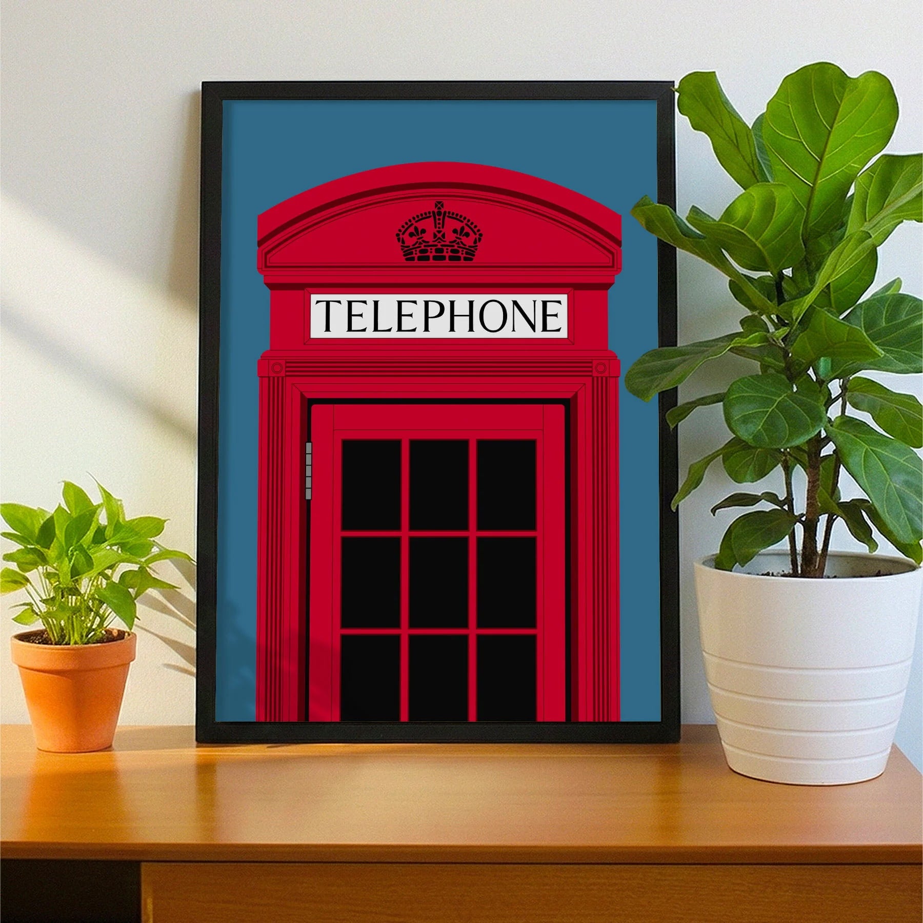 Framed print on sideboard beside a plant