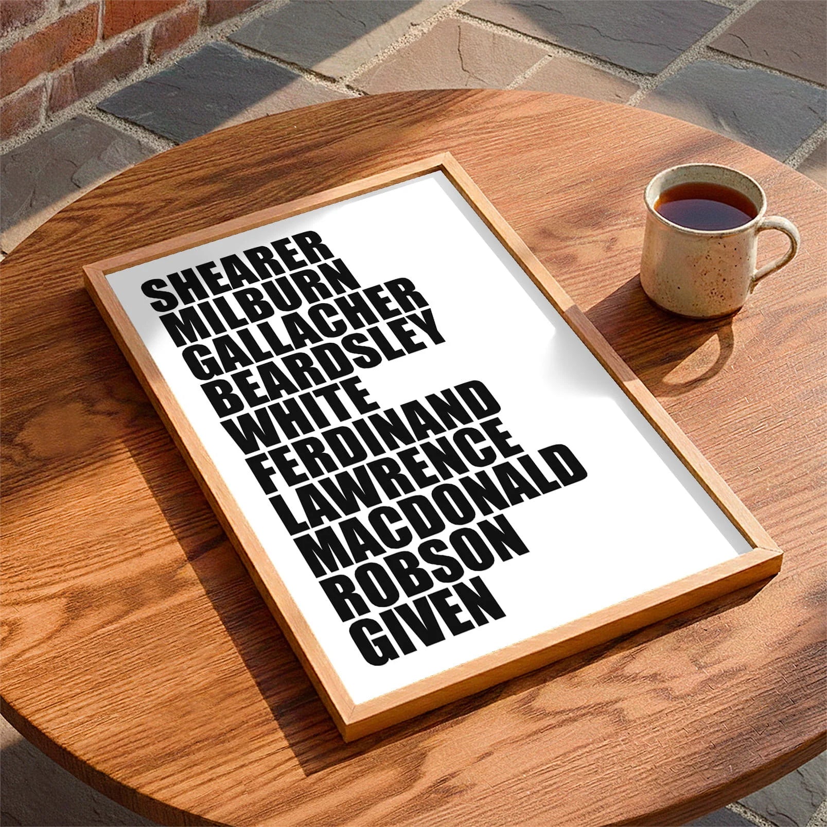 Framed print laying on a table beside a mug of tea