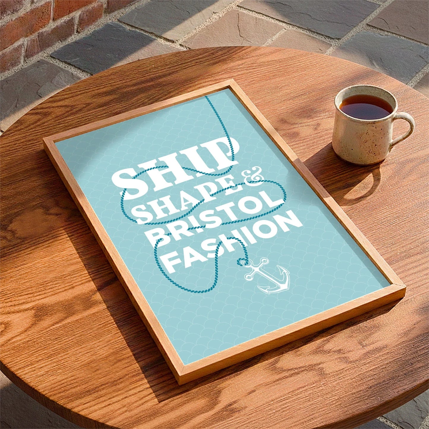 Framed print laying on a table beside a mug of tea