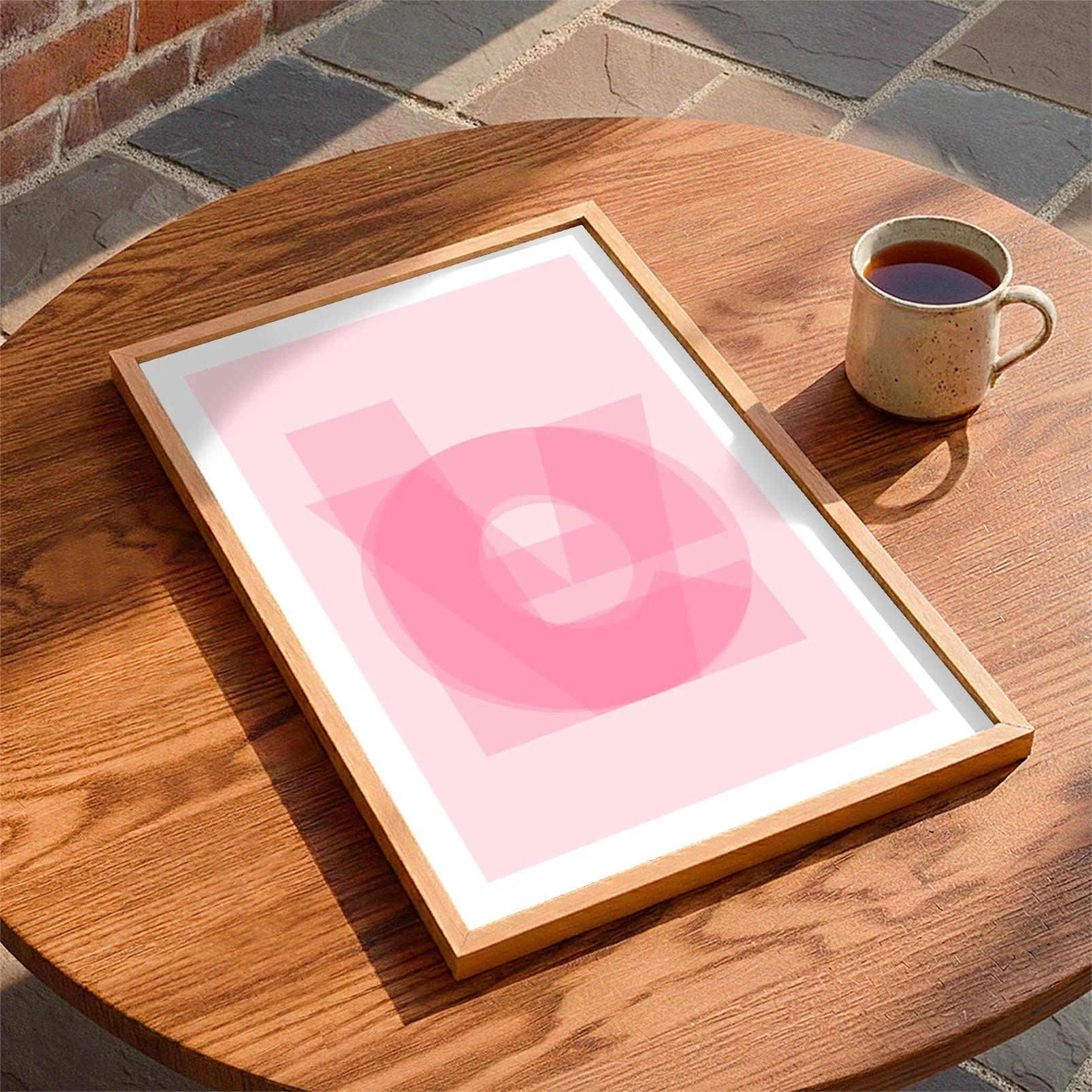 Framed print laying on a table beside a mug of tea