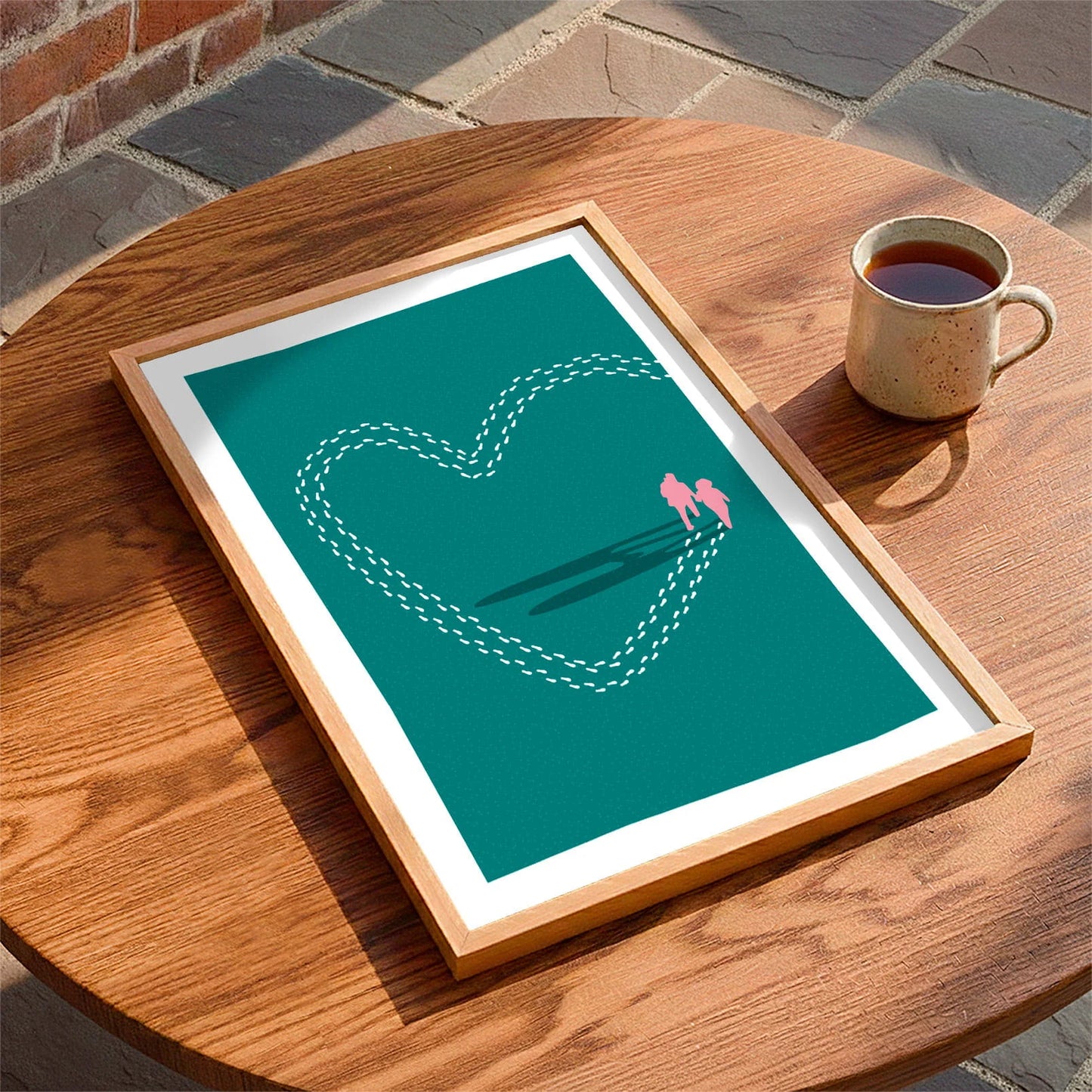 Framed print laying on a table beside a mug of tea