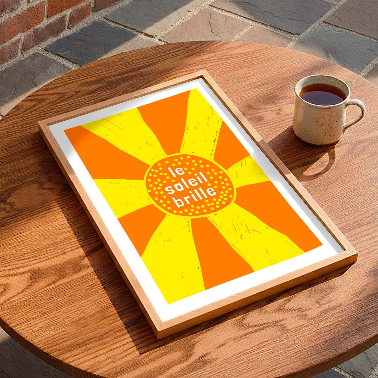 Framed print laying on a table beside a mug of tea