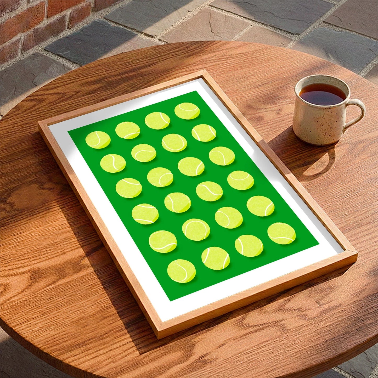 Framed print laying on a table beside a mug of tea