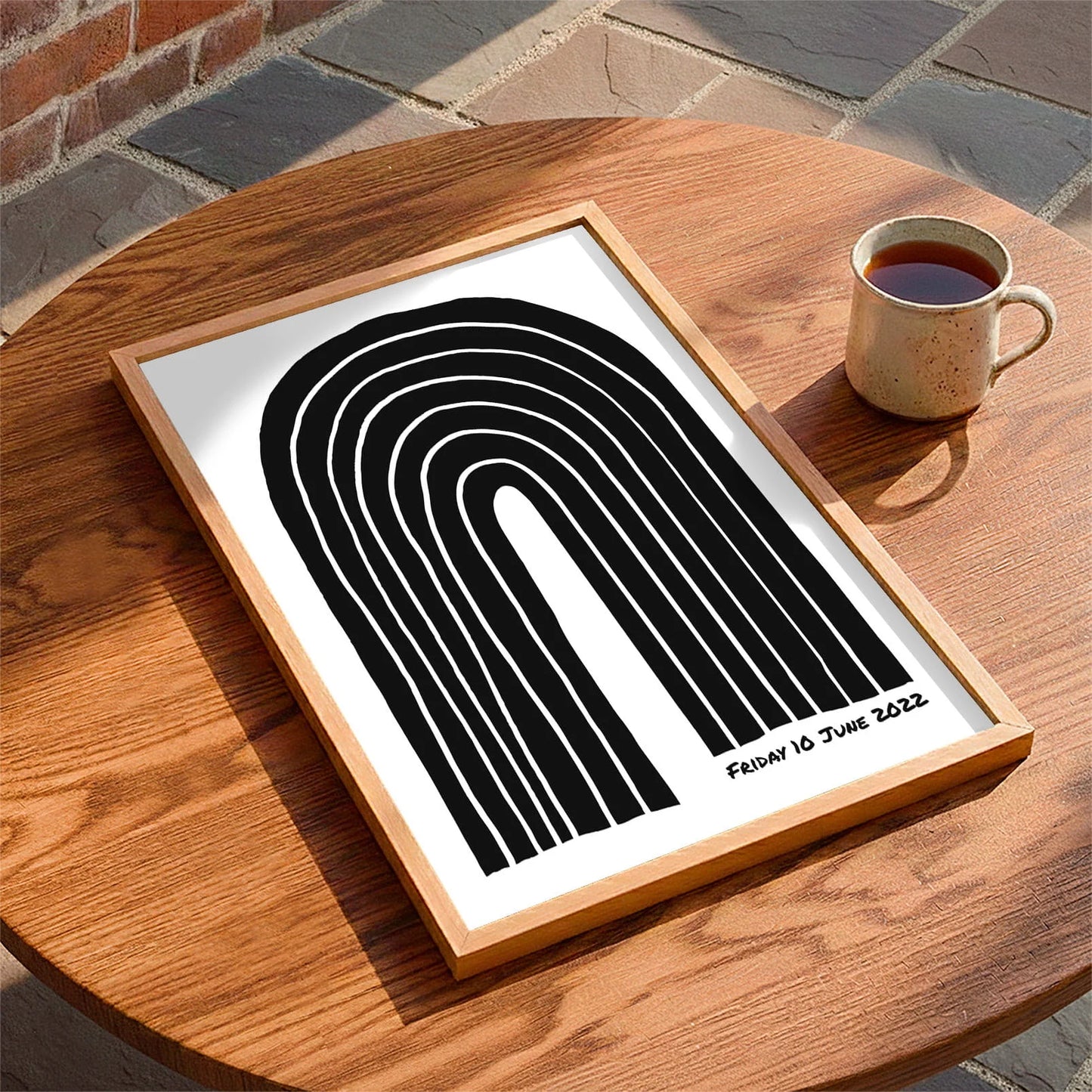 Framed print laying on a table beside a mug of tea