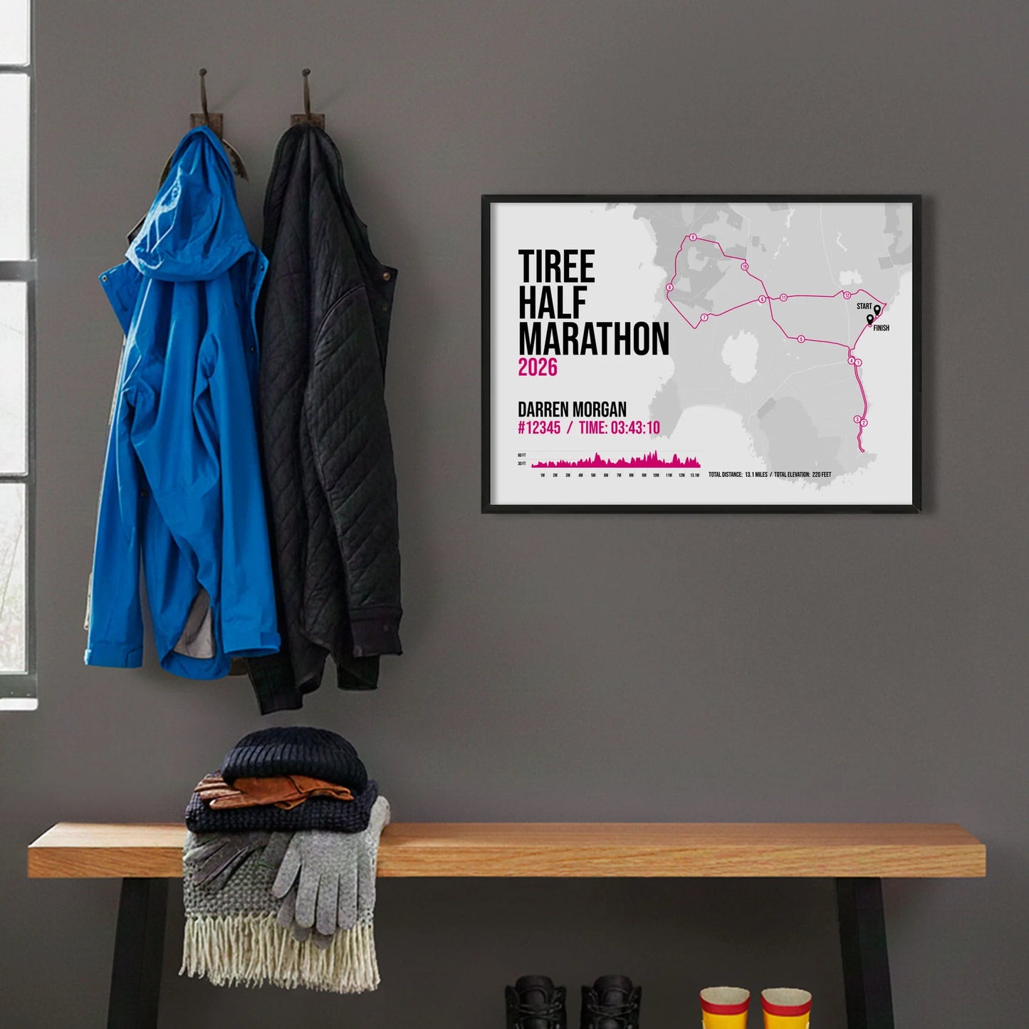 Framed print hanging on grey wall beside coats on hooks above walking boots and shows