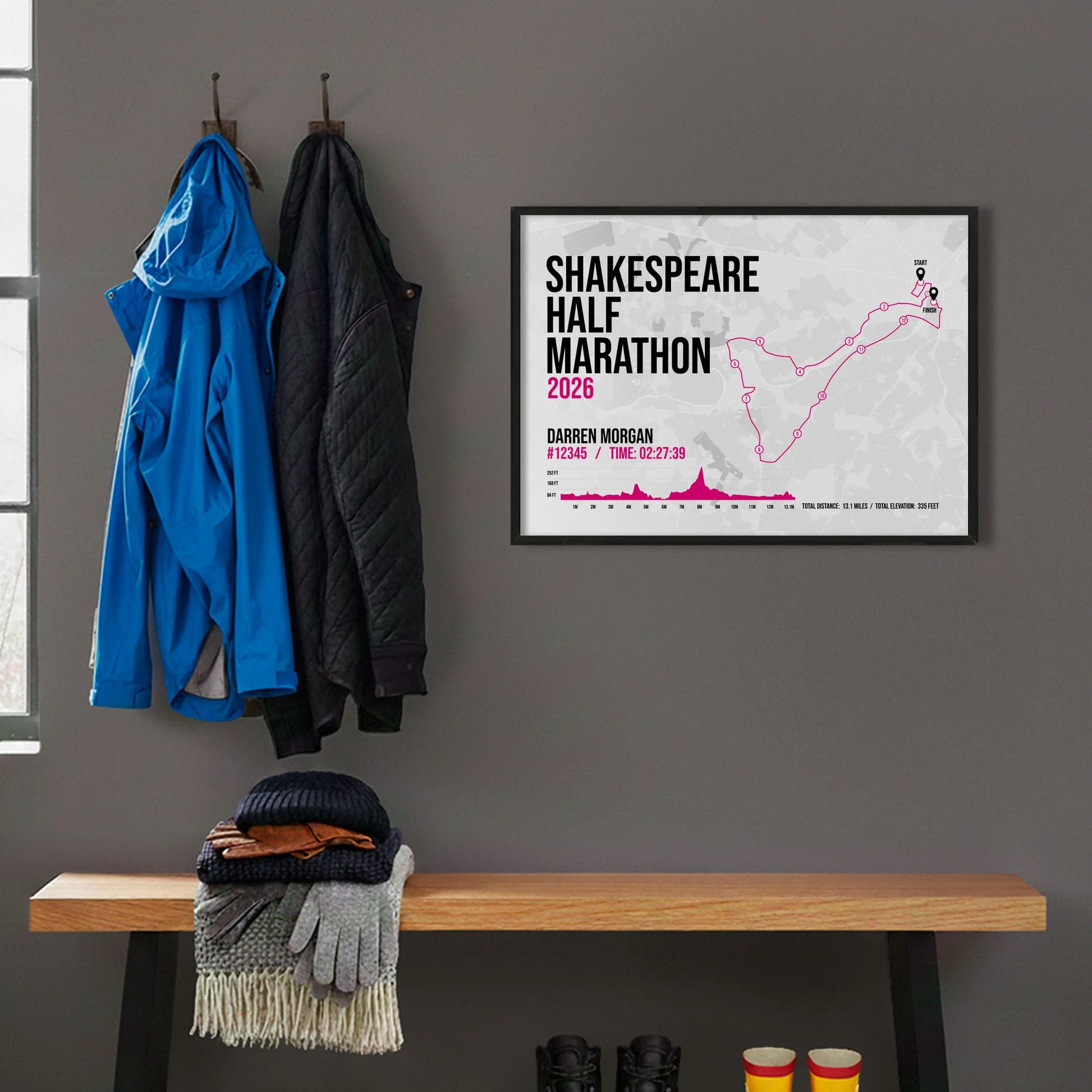 Framed print hanging on grey wall beside coats on hooks above walking boots and shows
